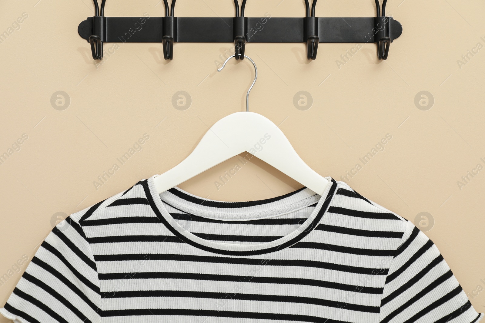 Photo of Hanger with striped t-shirt on beige wall