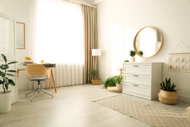 Photo of Stylish room interior with chest of drawers and round mirror