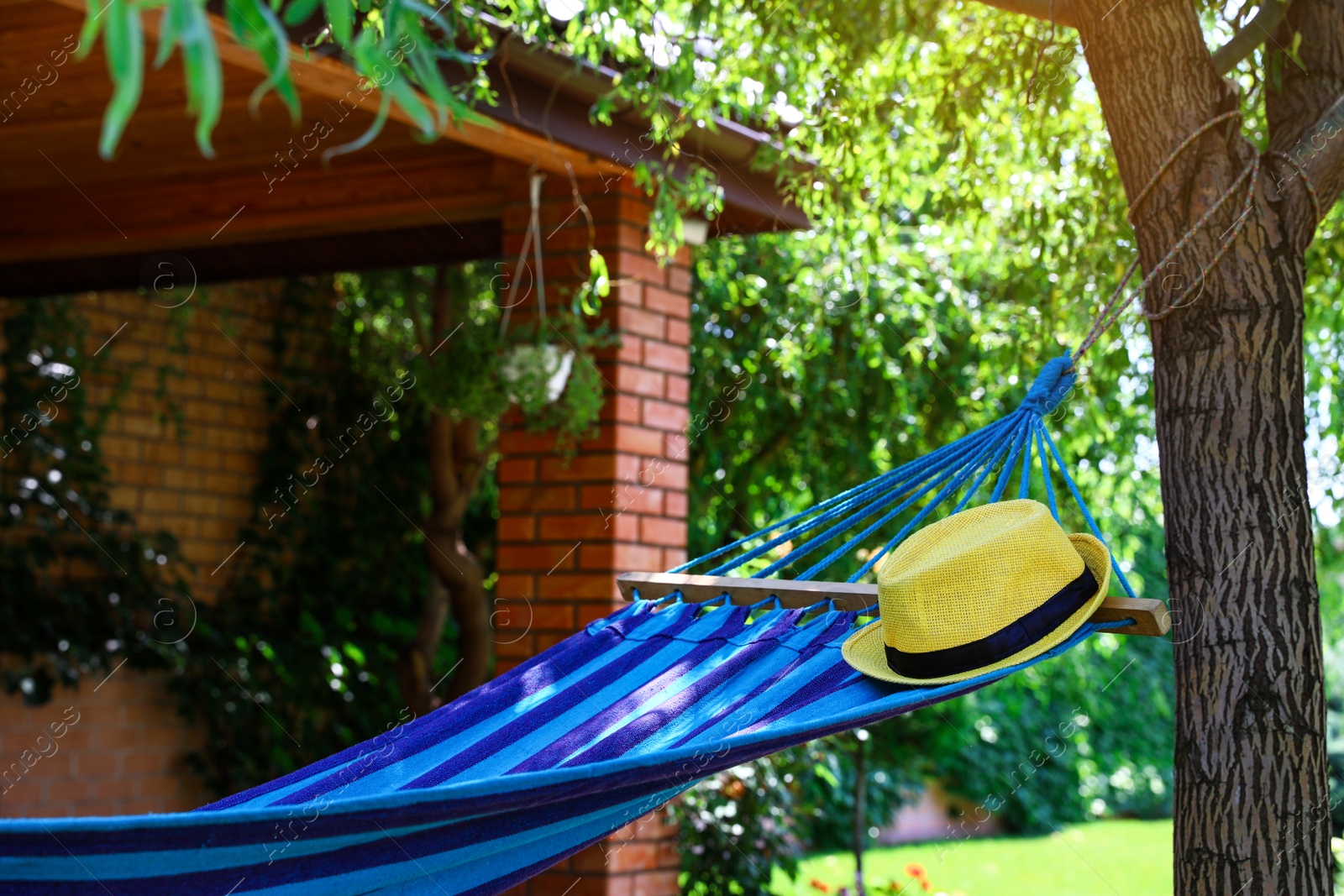 Photo of Comfortable blue hammock with hat outdoors on sunny day