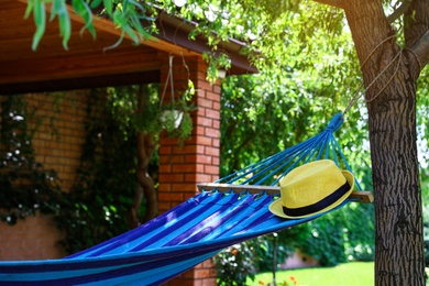 Comfortable blue hammock with hat outdoors on sunny day