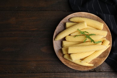 Photo of Tasty fresh yellow baby corns on wooden table, top view. Space for text