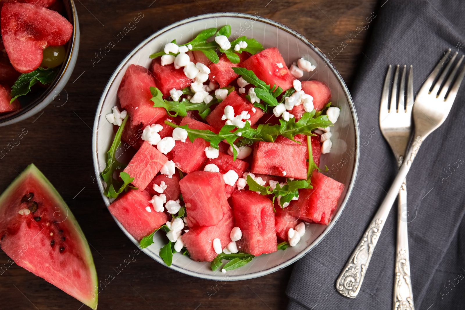 Photo of Delicious salad with watermelon, cheese and arugula on wooden table, flat lay