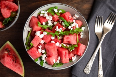 Photo of Delicious salad with watermelon, cheese and arugula on wooden table, flat lay