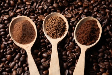 Photo of Spoons with different types of coffee on roasted beans, above view