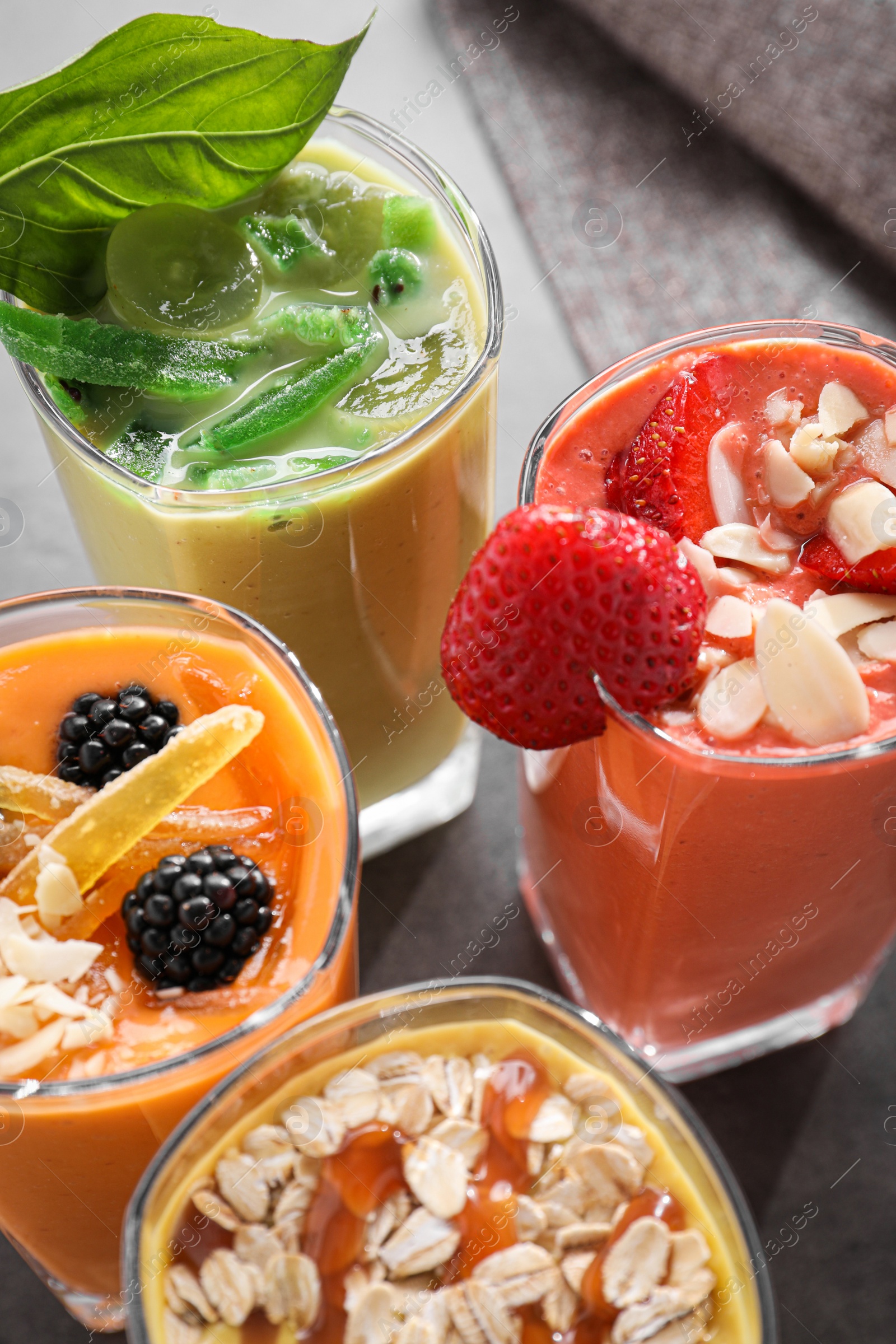 Photo of Many different delicious smoothies on grey table, closeup