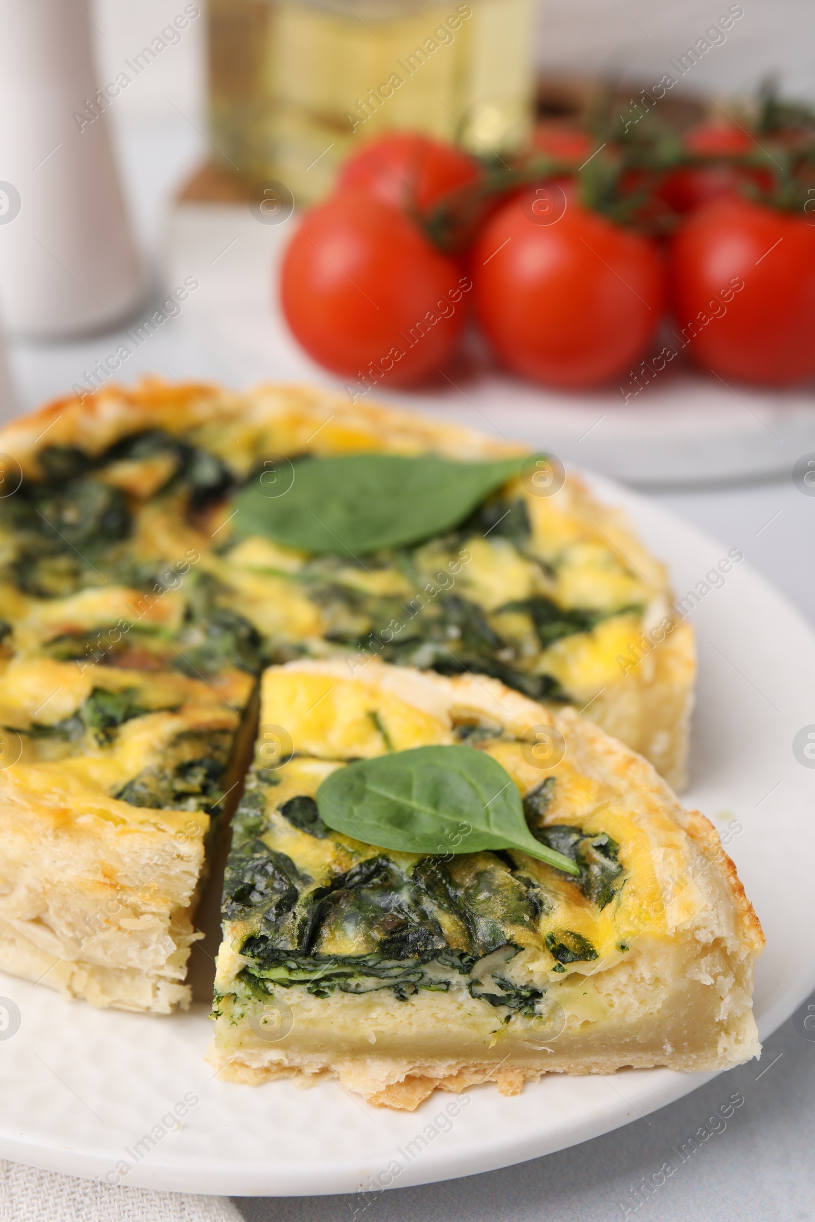 Photo of Delicious pie with spinach on white tiled table, closeup