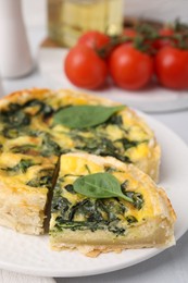 Photo of Delicious pie with spinach on white tiled table, closeup