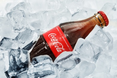 Photo of MYKOLAIV, UKRAINE - NOVEMBER 15, 2018: Bottle of Coca Cola on ice cubes, closeup