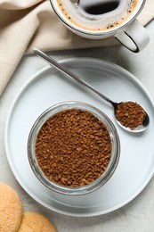 Photo of Spoon and glass jar with instant coffee on light table, flat lay