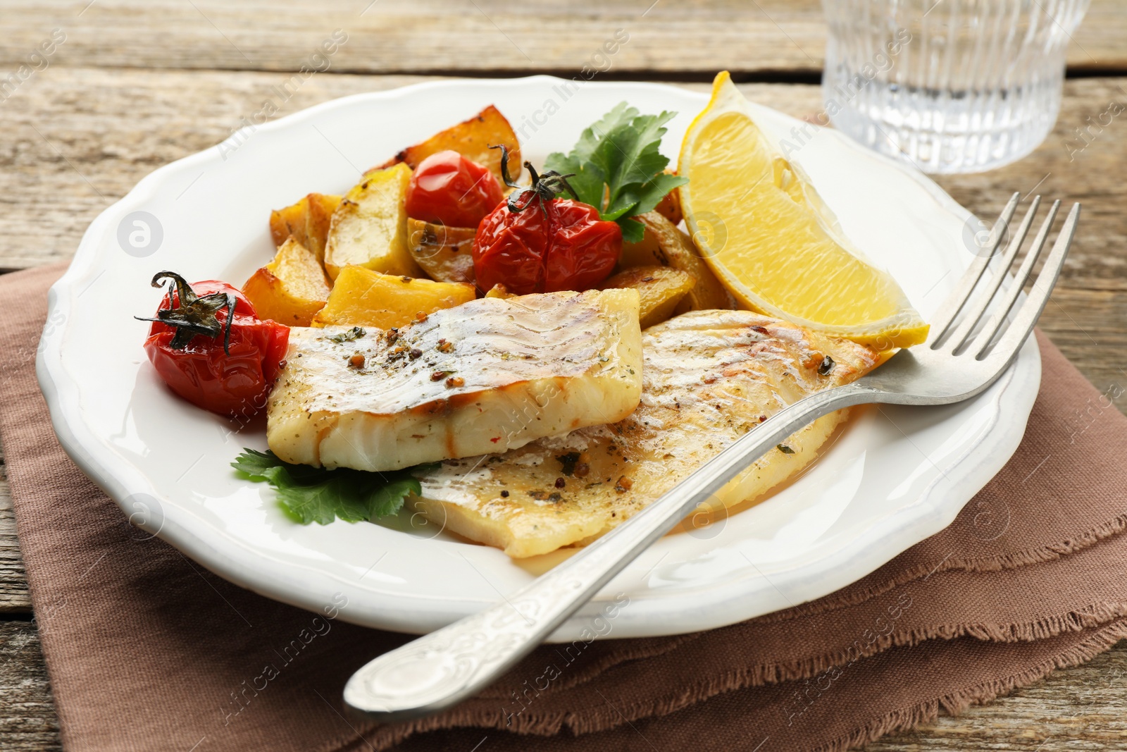 Photo of Tasty cod cooked with vegetables served on wooden table