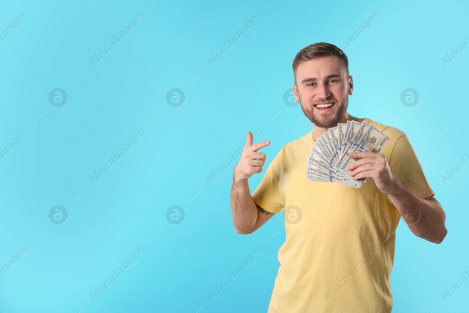 Photo of Portrait of happy young man with money on color background. Space for text