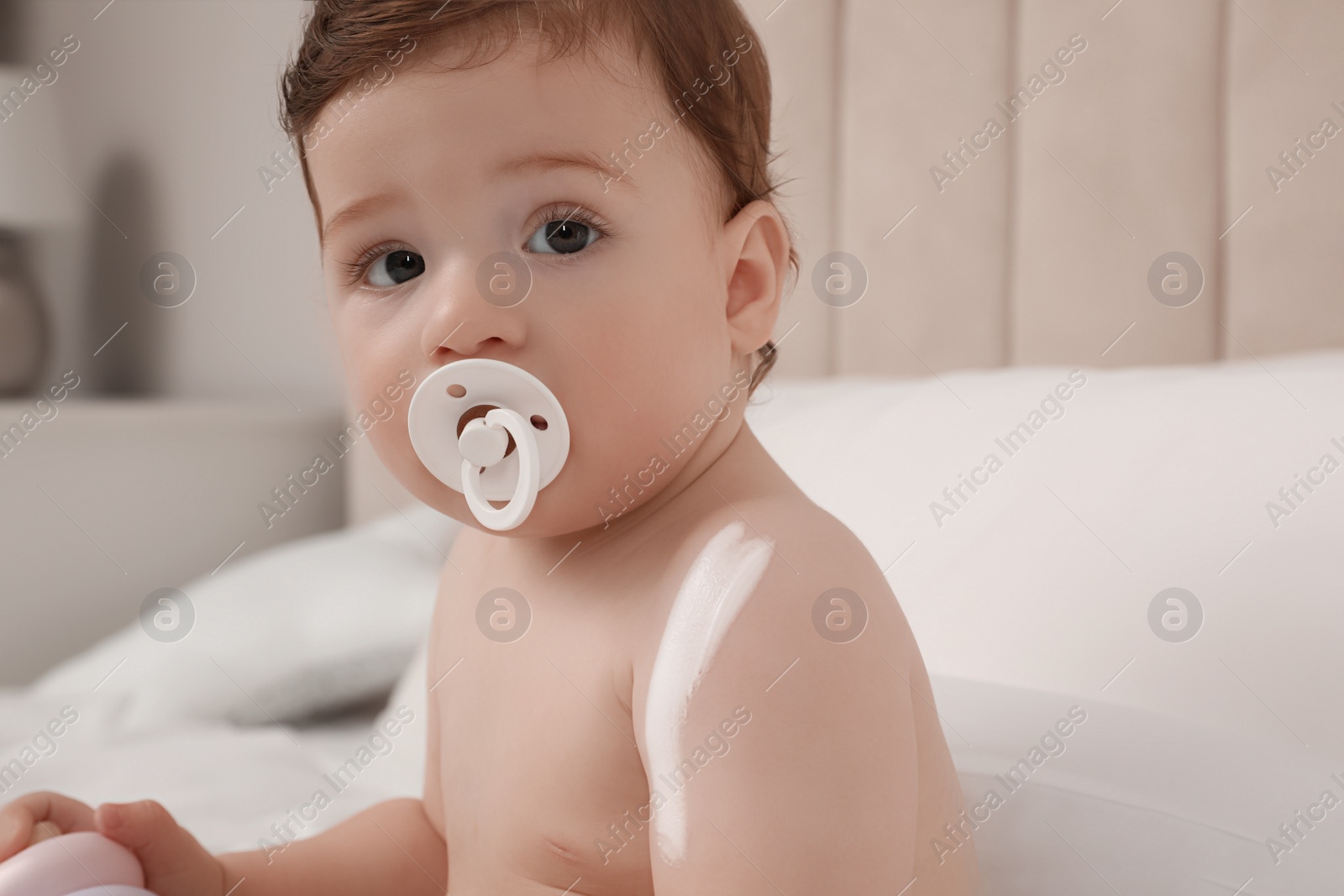 Photo of Cute little baby with cream on arm indoors