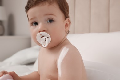 Photo of Cute little baby with cream on arm indoors