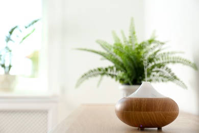 Modern aroma lamp on table against blurred background with space for text