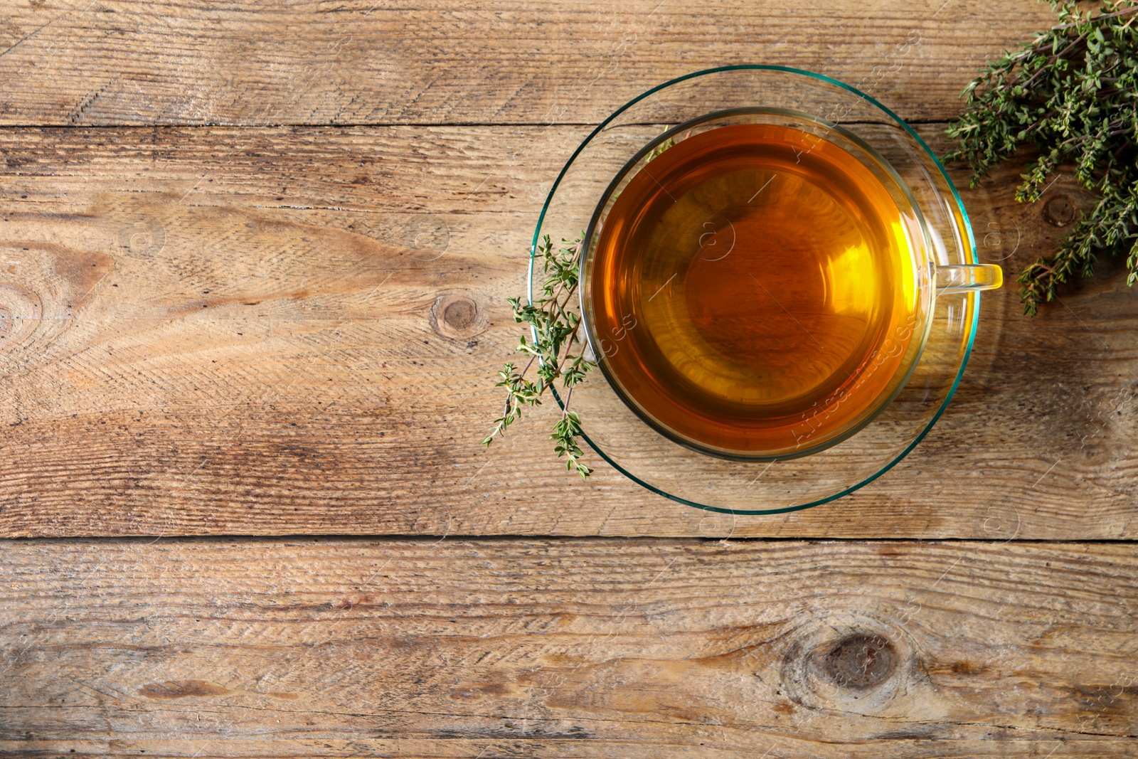 Photo of Aromatic herbal tea with thyme on wooden table, flat lay. Space for text