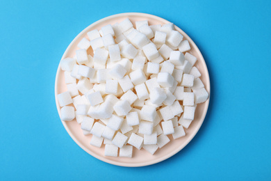 Photo of Refined sugar cubes on light blue background, top view