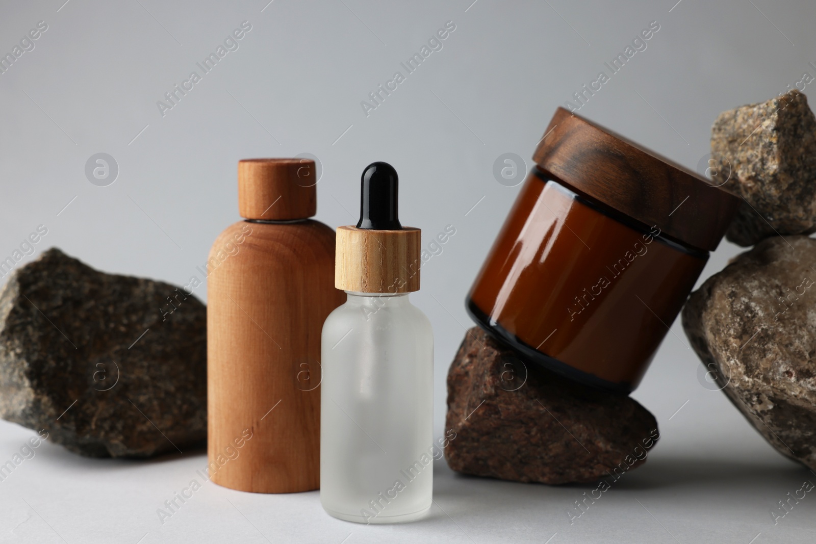 Photo of Different bottles, jar and stones on grey background, closeup