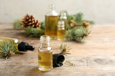 Photo of Bottle and pipette with conifer essential oil on wooden table. Space for text