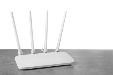 Photo of New modern Wi-Fi router on grey table against white background. Space for text