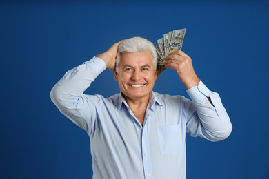 Photo of Happy senior man with cash money on blue background