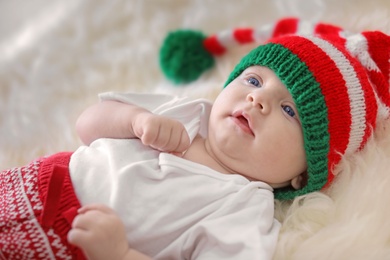Photo of Adorable baby in Christmas hat on fuzzy rug