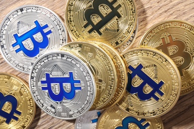 Photo of Shiny bitcoins on wooden background, flat lay. Digital currency