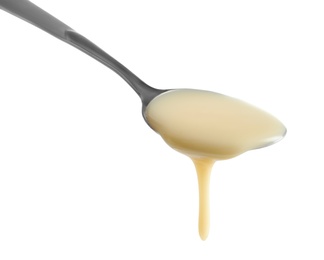 Photo of Spoon with condensed milk on white background, closeup. Dairy product