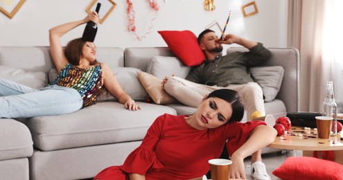 Image of Young woman sleeping at table and her friends suffering from hangover in messy room after New Year party. Banner design
