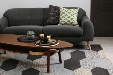 Photo of Sofa and freshly brewed coffee with decorative elements on wooden table in living room