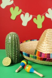 Photo of Composition with Mexican sombrero hat and maracas on green table, closeup
