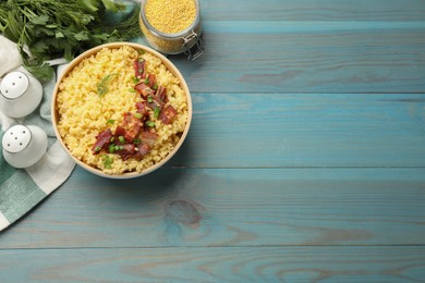 Photo of Tasty millet porridge with bacon, green onion and dill in bowl on light blue wooden table, flat lay. Space for text