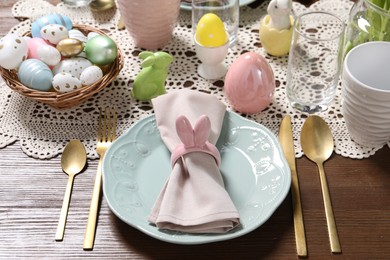 Photo of Festive table setting with napkin ring in shape of bunny ears, closeup. Easter celebration
