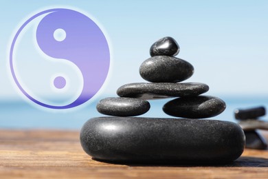 Image of Stack of stones on wooden table outdoors and Ying Yang symbol. Feng Shui philosophy 