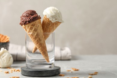 Photo of Tasty ice cream scoops in waffle cones on grey marble table, closeup. Space for text