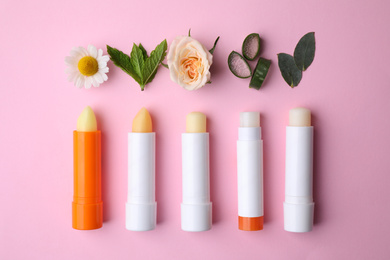 Photo of Flat lay composition with hygienic lipsticks on pink background
