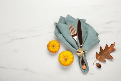Photo of Cutlery, napkin and autumn decoration on white marble background, flat lay with space for text. Table setting