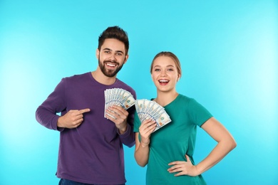 Photo of Happy young couple with money on color background