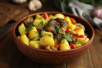 Photo of Tasty cooked dish with potatoes in earthenware on wooden table, closeup