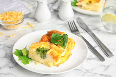 Photo of Tasty broccoli casserole served on white marble table