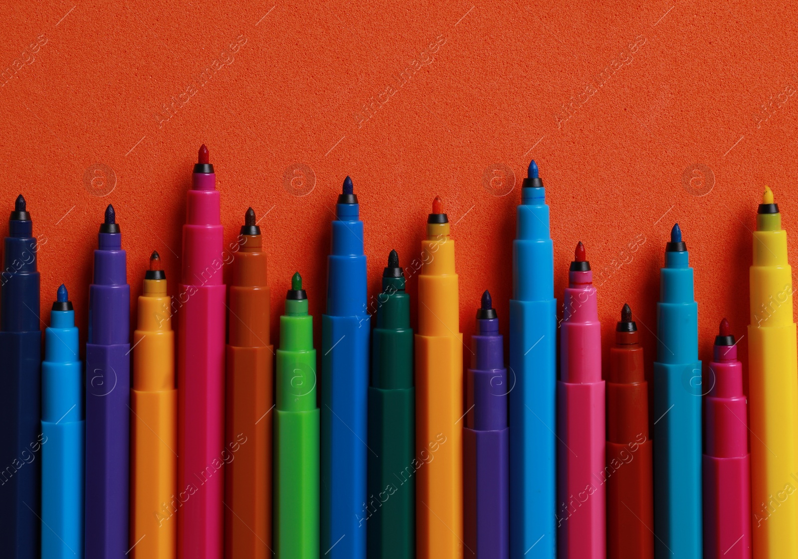 Photo of Set of felt tip pens on orange background, flat lay