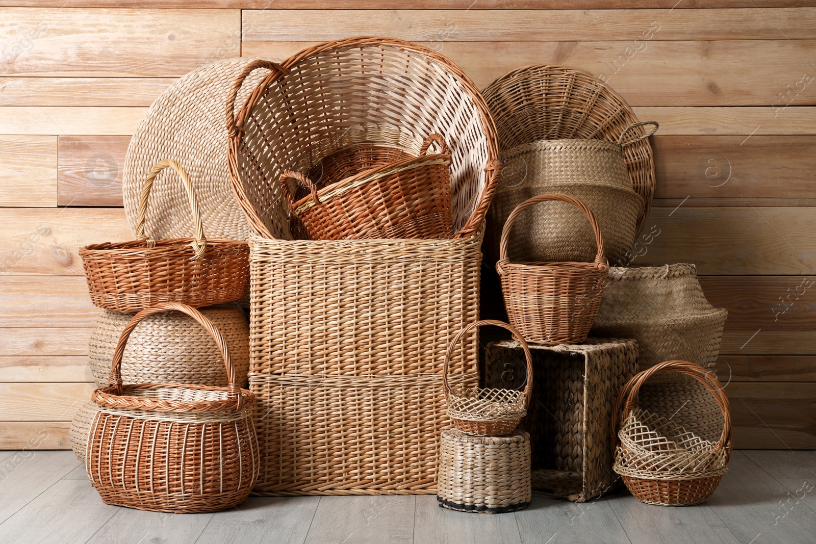 Photo of Many different wicker baskets made of natural material on floor near wooden wall