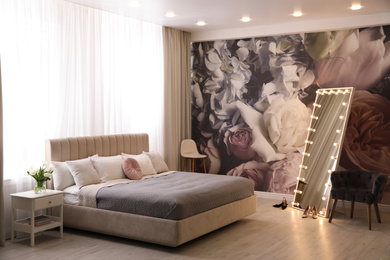 Photo of Beautiful room interior with large bed, mirror and floral pattern on wall