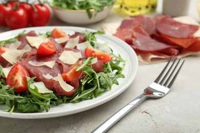 Photo of Delicious bresaola salad with parmesan cheese served on light grey textured table, closeup