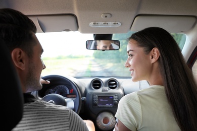 Photo of Young couple in car on road trip. Back view