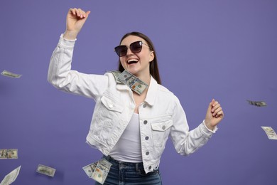 Photo of Happy woman under money shower on purple background