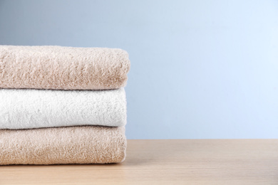 Photo of Stack of clean bath towels on wooden table. Space for text