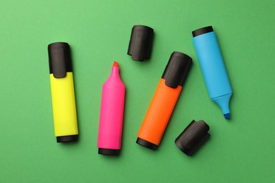 Photo of Bright color markers on green background, flat lay