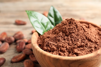 Photo of Bowl with cocoa powder on wooden table, closeup. Space for text