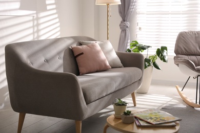 Photo of Stylish living room interior with comfortable sofa and wooden table