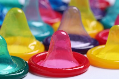 Photo of Colorful condoms on white background, closeup view. Safe sex